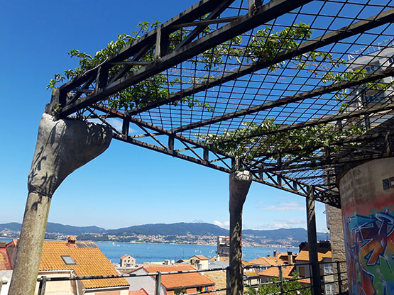 Macetas colgantes de hormigón enganchadas a los postes de la pérgola existente
